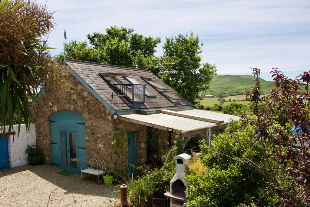 a small house with a blue door and a roof at Commonstone Barn in Llangennith