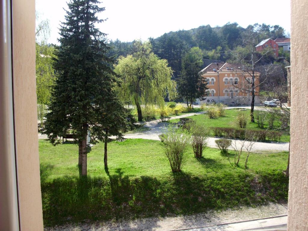 uma janela com vista para um pátio com uma árvore e um edifício em Apartments Bokan em Cetinje