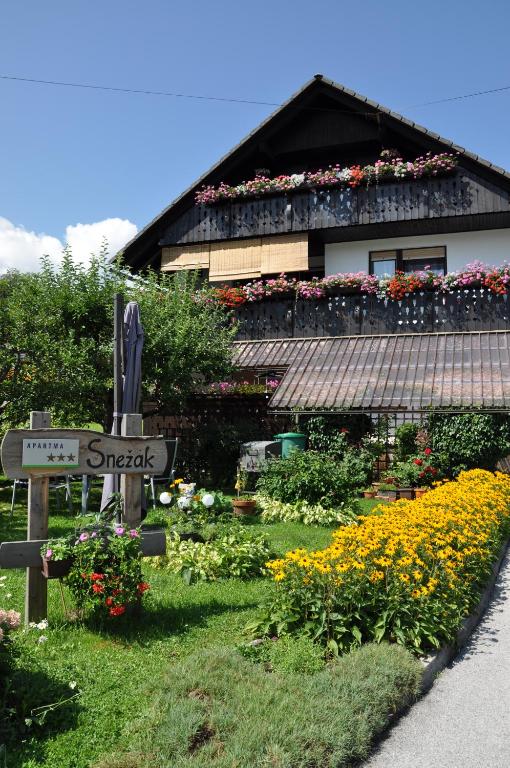 un cartello stradale di fronte a una casa con fiori di Snežak (Snowman) a Bohinj