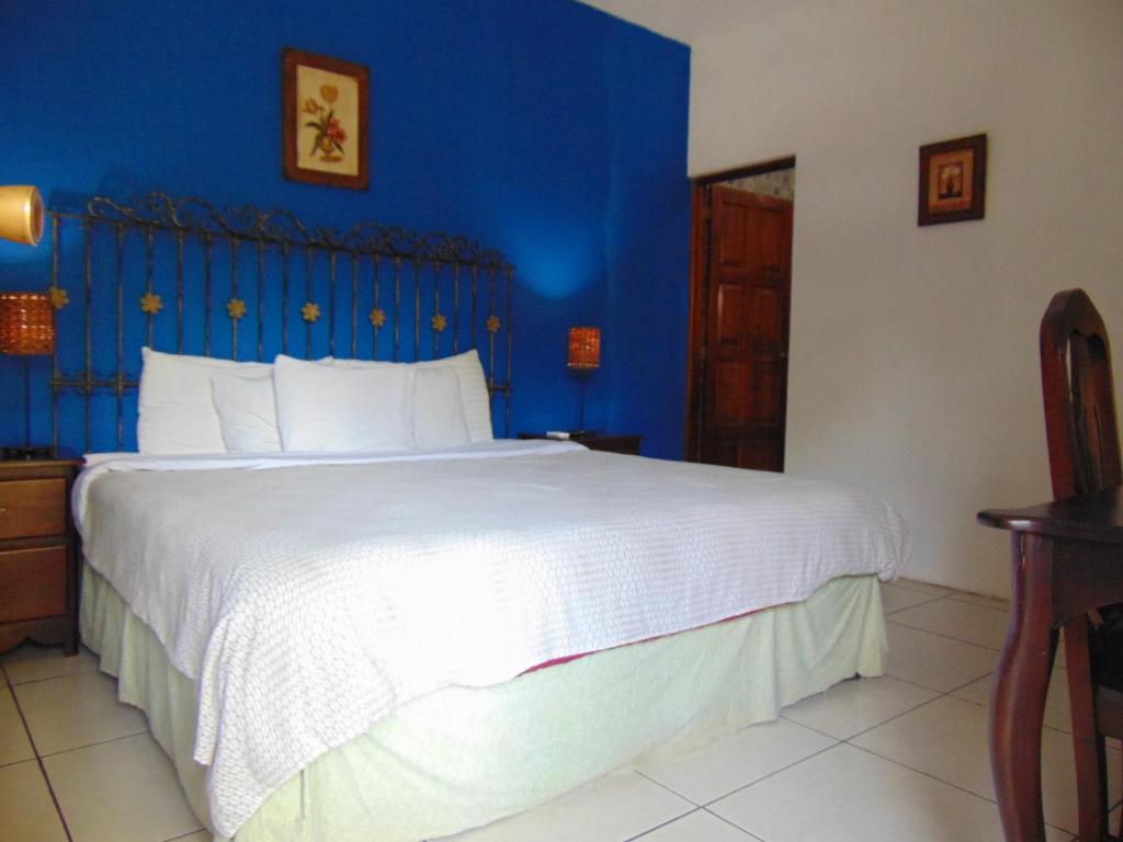 1 dormitorio con 1 cama grande y pared azul en Managua Hills en Managua