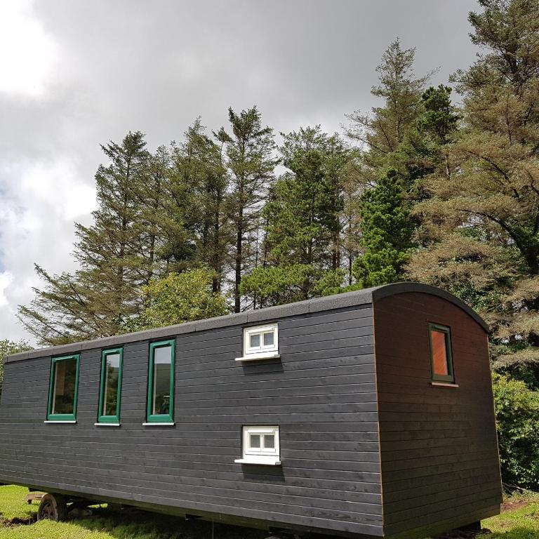 una piccola casa nera con finestre e alberi di Annascaul Train Carriage suit couple and 2 children ad Anascaul
