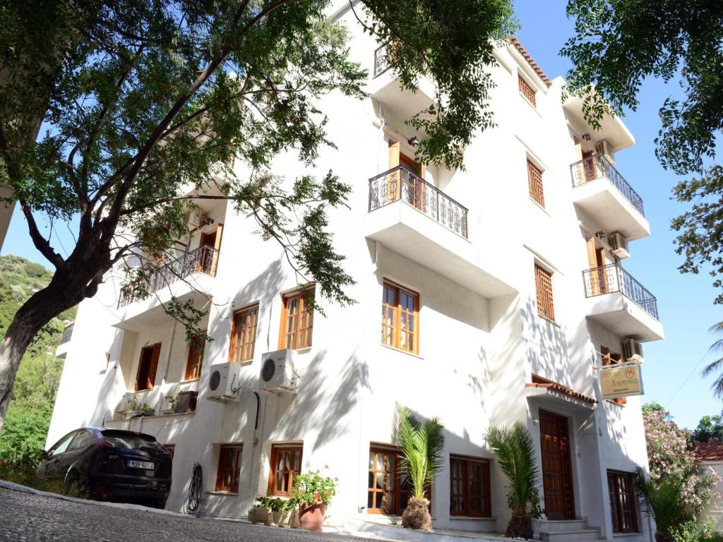 un edificio blanco con árboles delante de él en Anthemis Hotel en Agios Kirykos