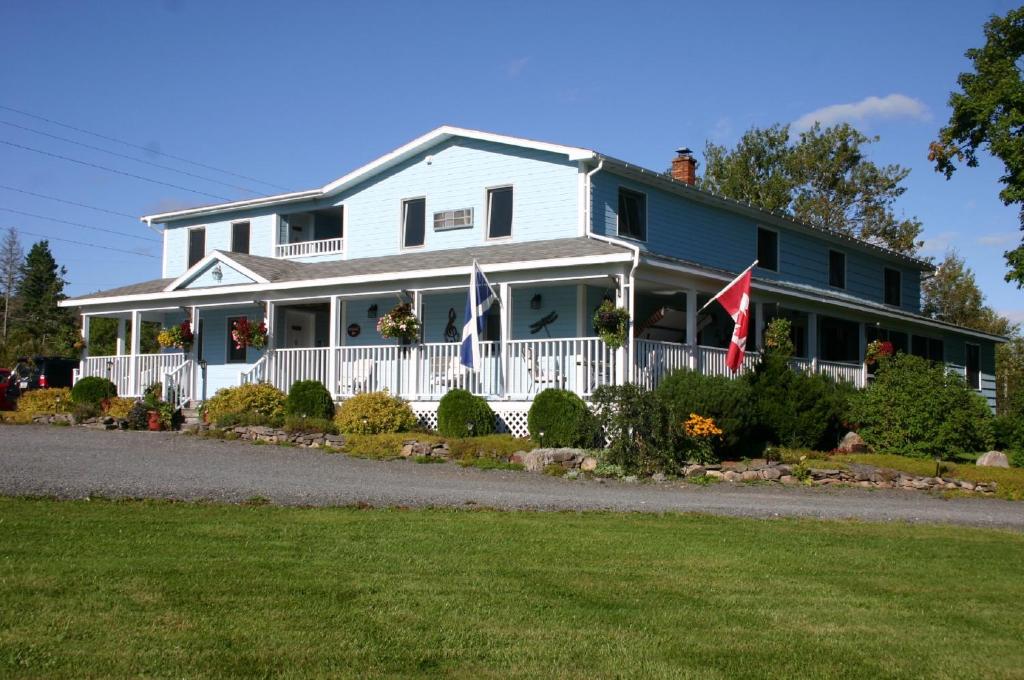 a white house with a white fence and a flag at Auld Farm Inn B&B in Baddeck