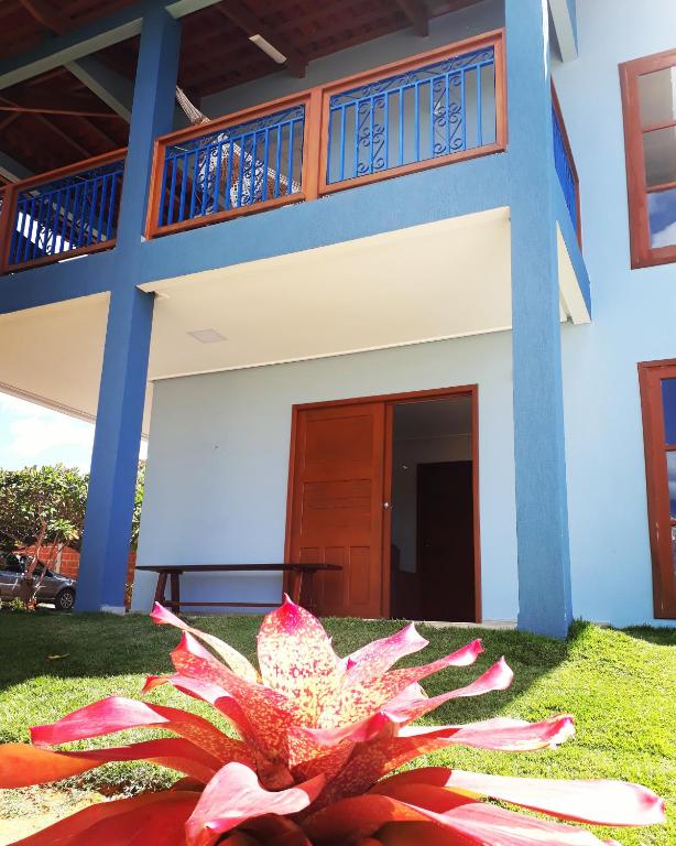 a pink flower in front of a house at Vivendas da Serra Chalés in Martins