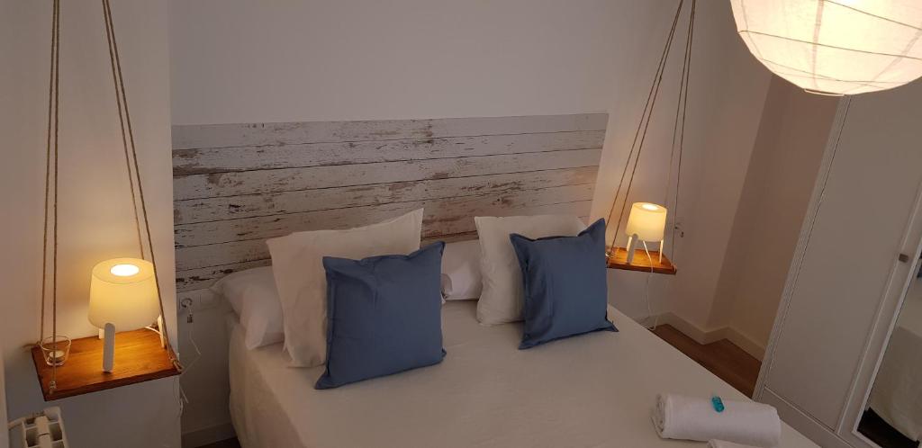 a bedroom with a bed with blue pillows and two lights at Alojamientos Segóbriga Rural (Tahona) in Segorbe