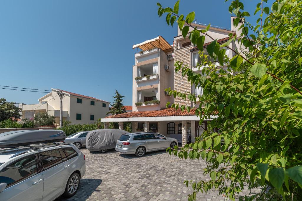 een gebouw met auto's geparkeerd op een parkeerplaats bij Apartments Vojin in Trogir