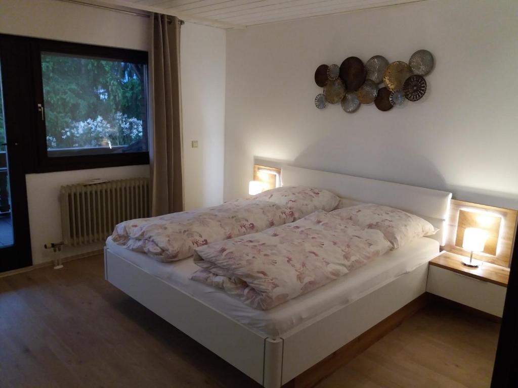 Cama en habitación con 2 lámparas y ventana en Ferienwohnung Lingenfelder en Bad Dürkheim