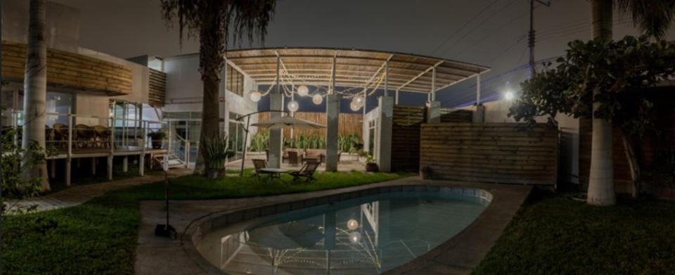 a swimming pool in the yard of a house at night at Hotel Avenida en Arica in Arica