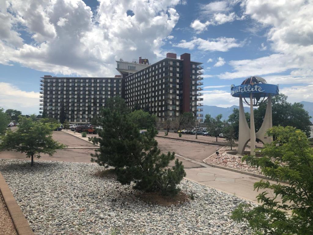 コロラドスプリングスにあるSatellite Hotelの青いホテルの看板と木が並ぶ大きな建物