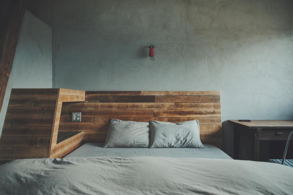 a bed with a wooden headboard in a bedroom at kagelow Mt.Fuji Hostel Kawaguchiko in Fujikawaguchiko