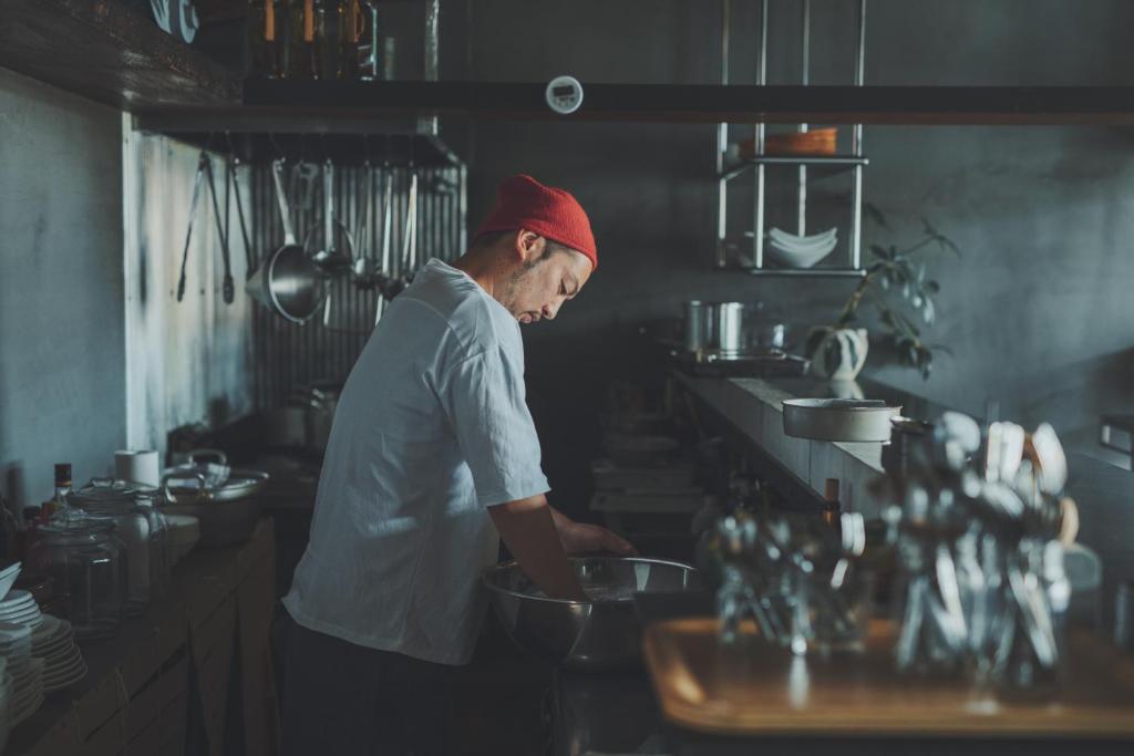 a man in a kitchen preparing food in a bowl at kagelow Mt.Fuji Hostel Kawaguchiko in Fujikawaguchiko