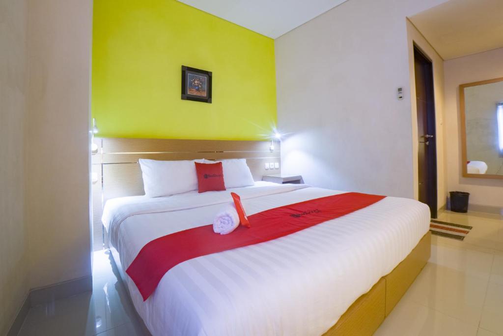 a bedroom with a large white bed with a green wall at Budget Hotel Ambon in Ambon