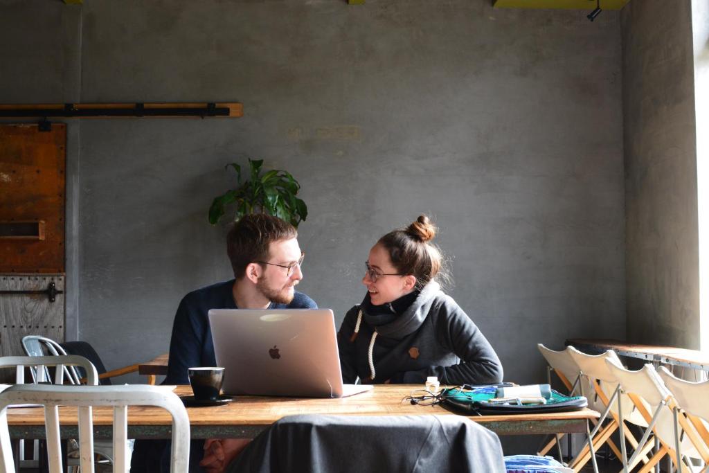 a man and woman sitting at a table with a laptop at kagelow Mt.Fuji Hostel Kawaguchiko in Fujikawaguchiko