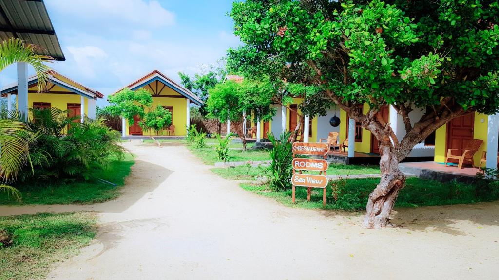 un cartello di fronte a una casa con un albero di Exotic Beach Hotel ad Arugam