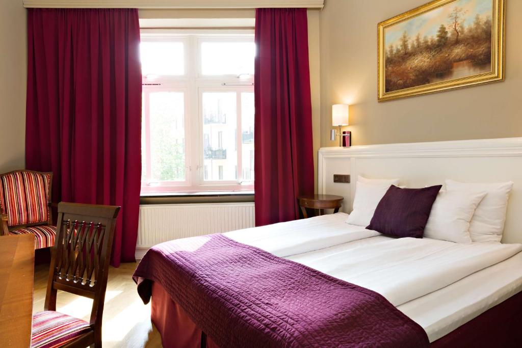 a bedroom with a large bed with red curtains at Hotel Vasa, Sure Hotel Collection by Best Western in Gothenburg