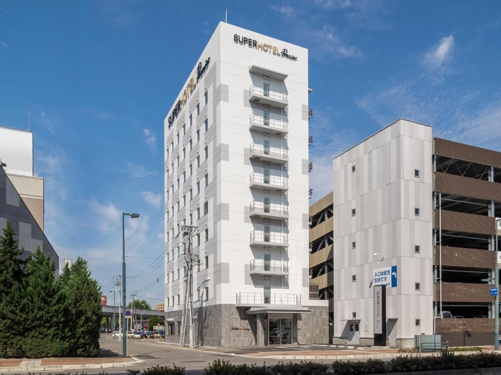 a tall white building next to a street at Super Hotel Premier Obihiro Ekimae in Obihiro