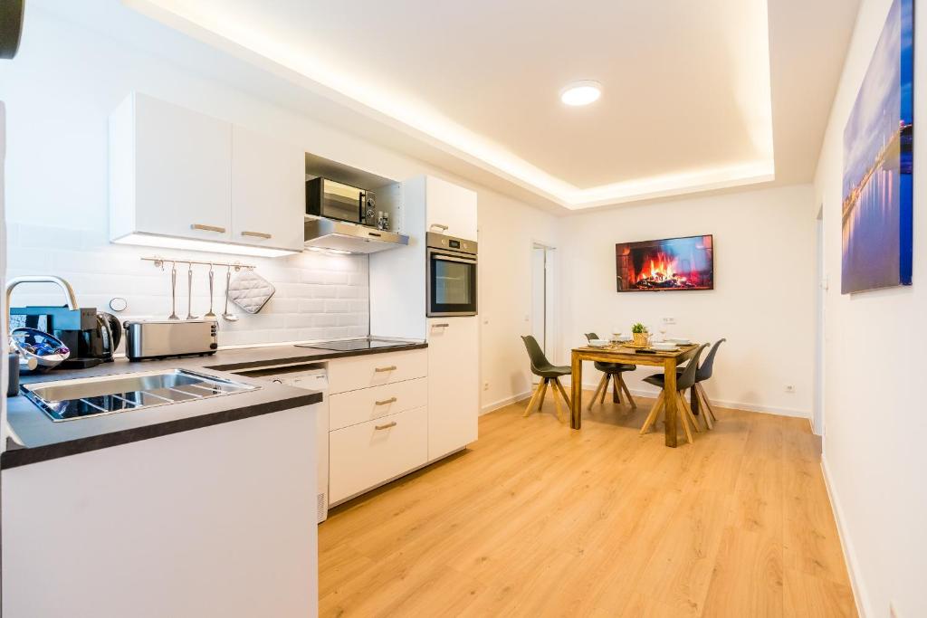 una cocina con armarios blancos y una mesa con sillas. en Centerapartments Marienstrasse en Düsseldorf