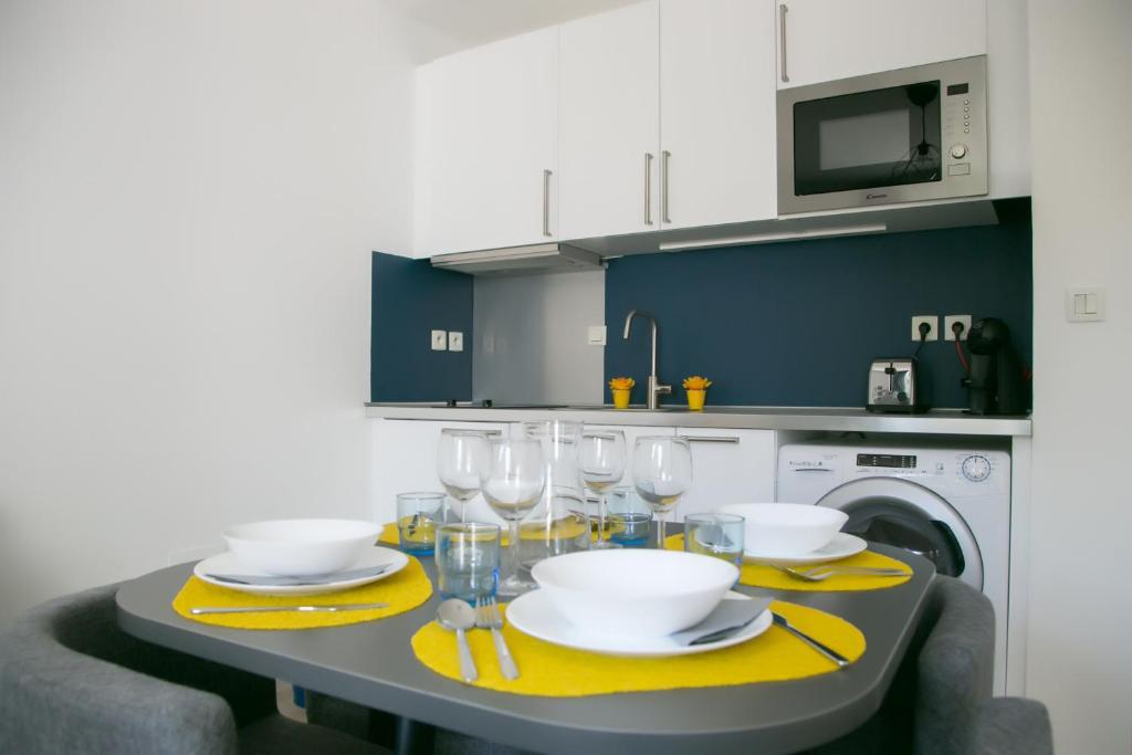 une cuisine avec une table avec des assiettes et des verres à vin dans l'établissement T2 proche Centre historique Gare St-Roch avec Parking, à Montpellier