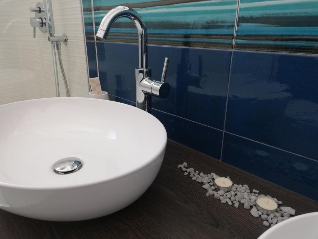 La salle de bains est pourvue d'un lavabo blanc et de carrelage bleu. dans l'établissement Kaloneiro Guest House, à Corigliano dʼOtranto