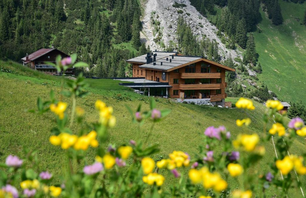 a house on a hill with flowers in the foreground at LUX ALP CHALET am Arlberg in Warth am Arlberg