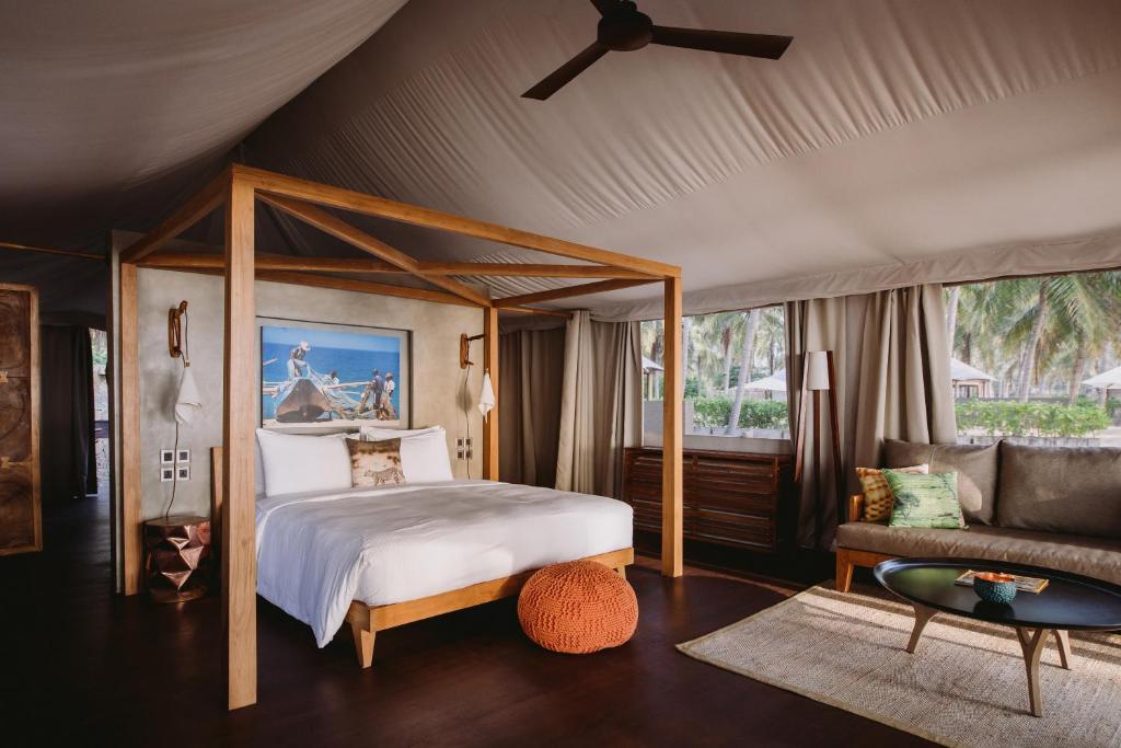 Karpaha Sands في باسيكودا: غرفة نوم مع سرير مظلة وأريكة