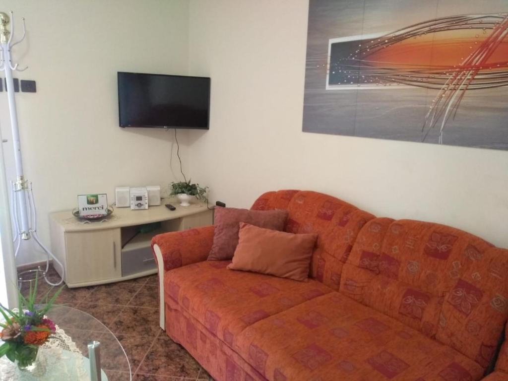 a living room with an orange couch and a tv at Szemes Apartman Balaton in Balatonszemes