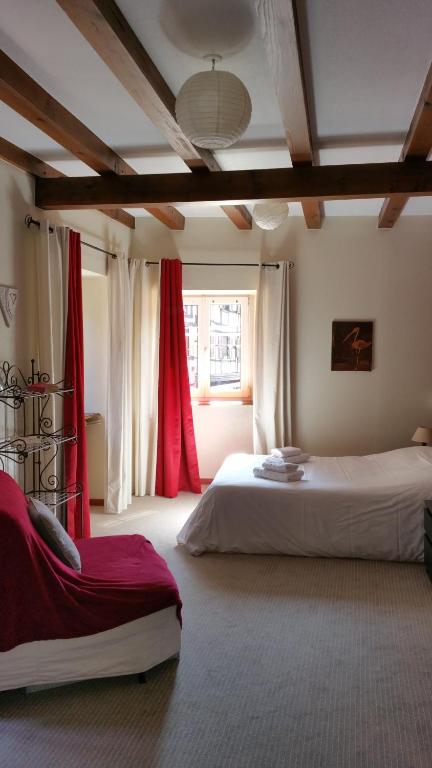 een slaapkamer met 2 bedden en rode gordijnen bij Chambres touristiques La Cour Des Hôtes in Obernai