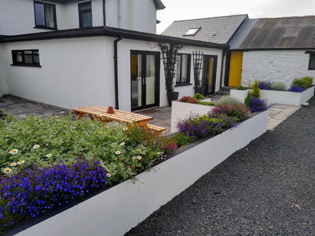 a house with a bench and flowers in front of it at Dunseverick Ramblers Rest in Bushmills