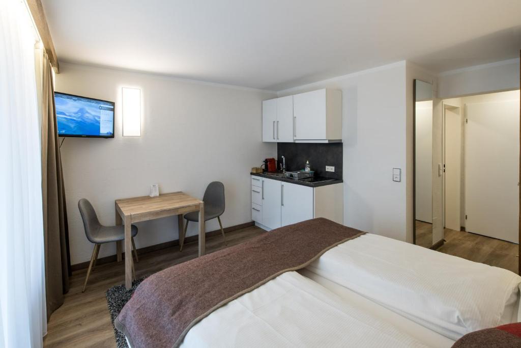 a bedroom with a bed and a table and a kitchen at Apartments Butterfly Zermatt in Zermatt