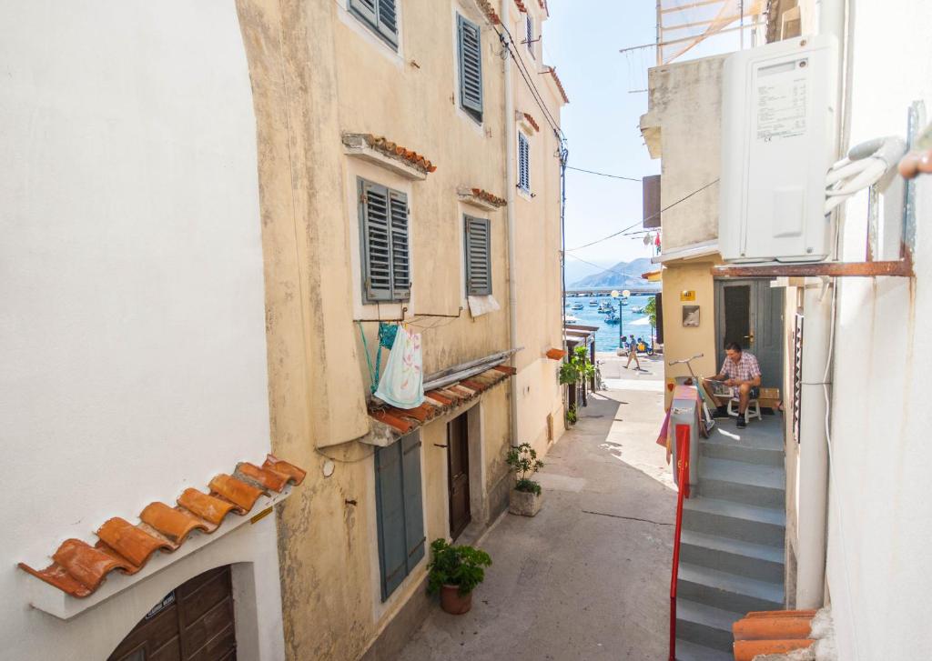 an alleyway between two buildings with people walking down it at Studio Marin in Baška