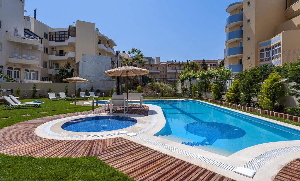 a swimming pool with an umbrella next to a building at Leonidas Hotel & Apartments in Rethymno