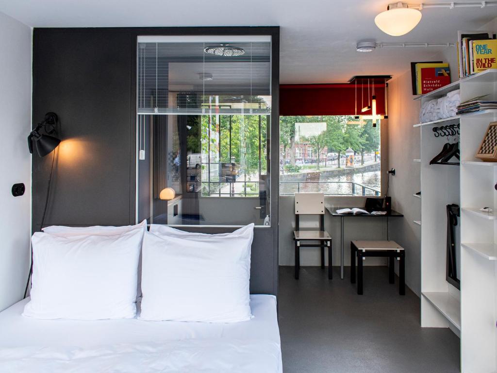 a bedroom with a bed and a table and a window at SWEETS - Hortusbrug in Amsterdam