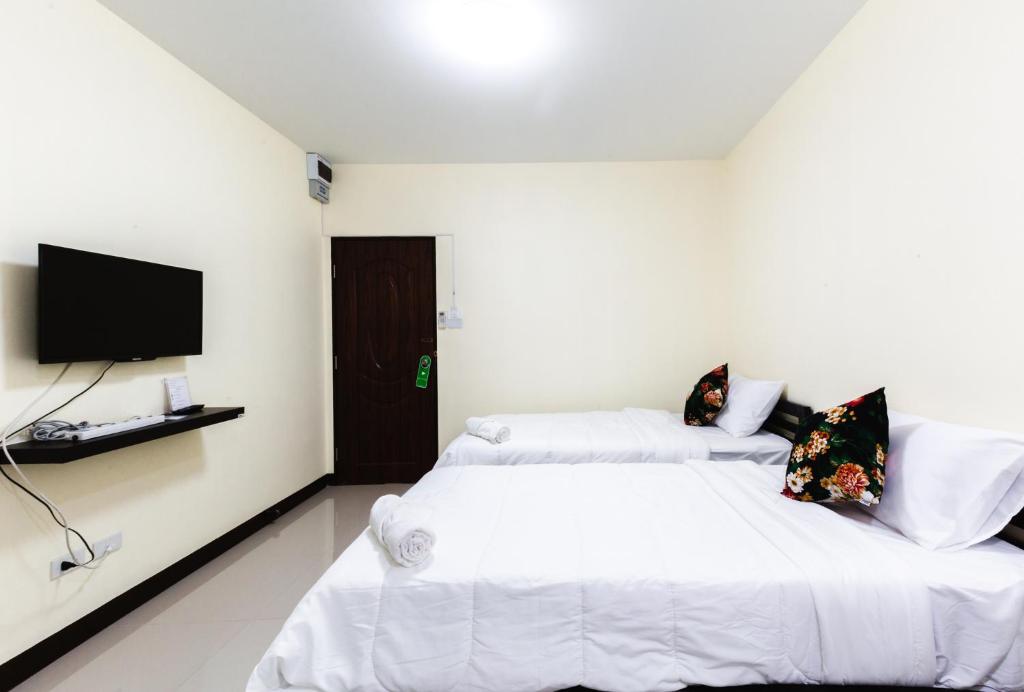 a bedroom with two beds and a flat screen tv at House of Happiness in Bangkok