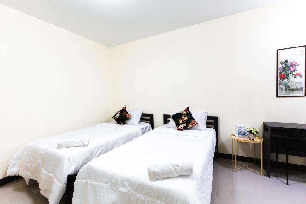 A simple twin room with separate beds and a small side table.
