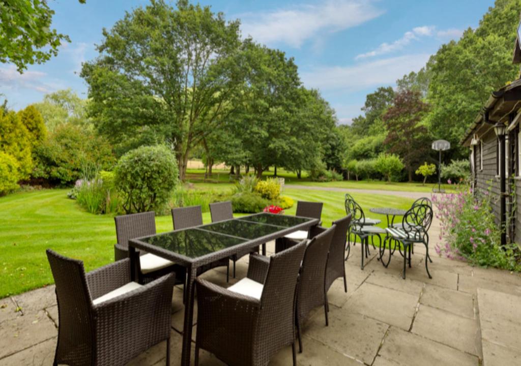 un patio con mesa, sillas y césped en White Lodge House, en Guildford