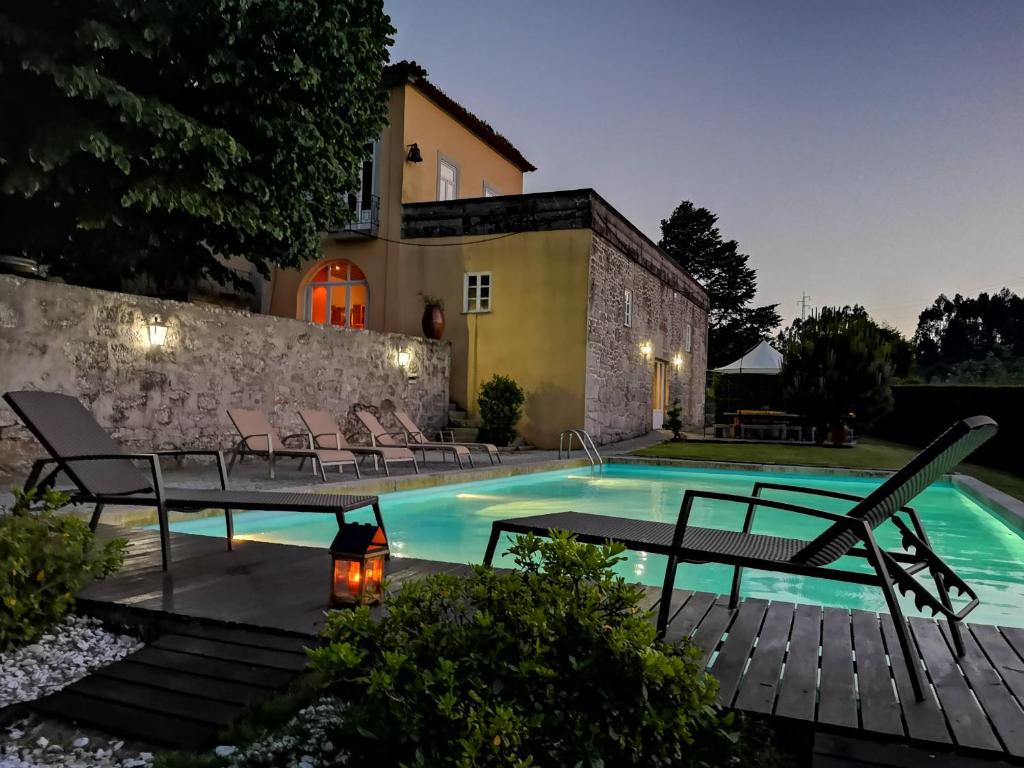 a swimming pool with chairs and a house at Quinta S. Romao do Neiva in Castelo do Neiva