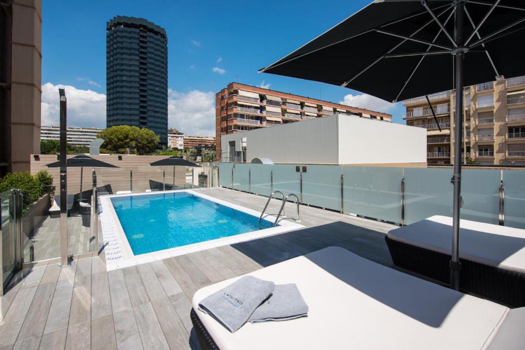 a swimming pool on top of a building with an umbrella at Catalonia Rigoletto in Barcelona