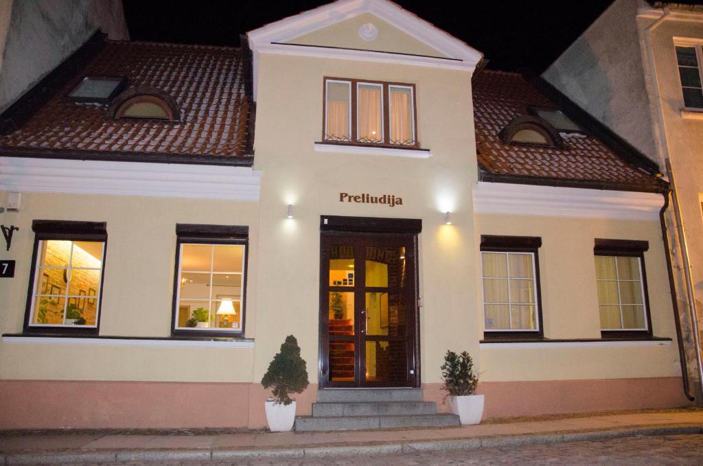 a white house with a front door at night at Preliudija in Klaipėda