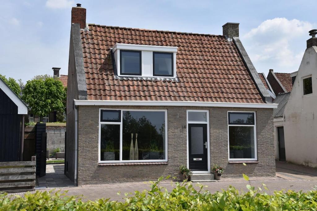 a brick house with a red roof at Sfeervol vakantiehuis in Holwerd in Holwerd