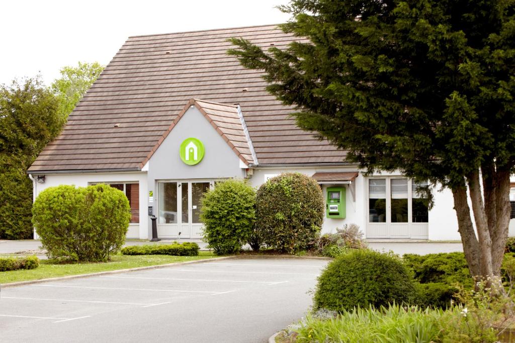 a white house with a green sign on it at Campanile Dreux in Dreux