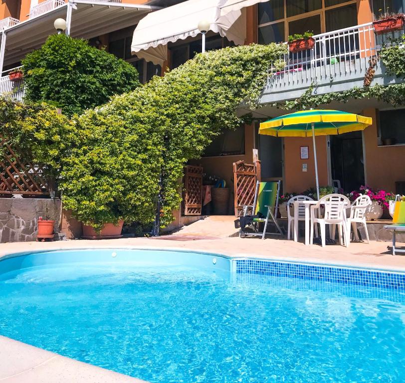 uma piscina com um guarda-sol, uma mesa e cadeiras em Albergo Hotel Garden Ristorante em Tabiano