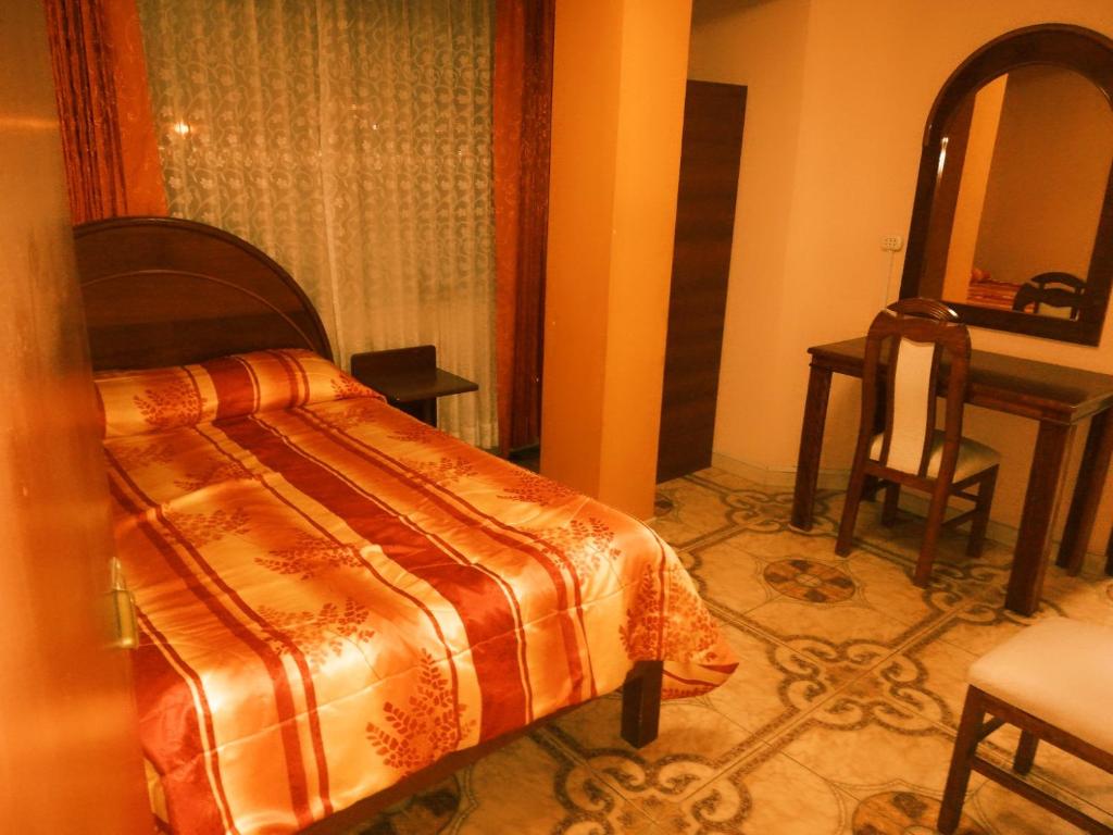 a bedroom with a bed and a table and a mirror at Hostal Estrellita Dorada in Tacna