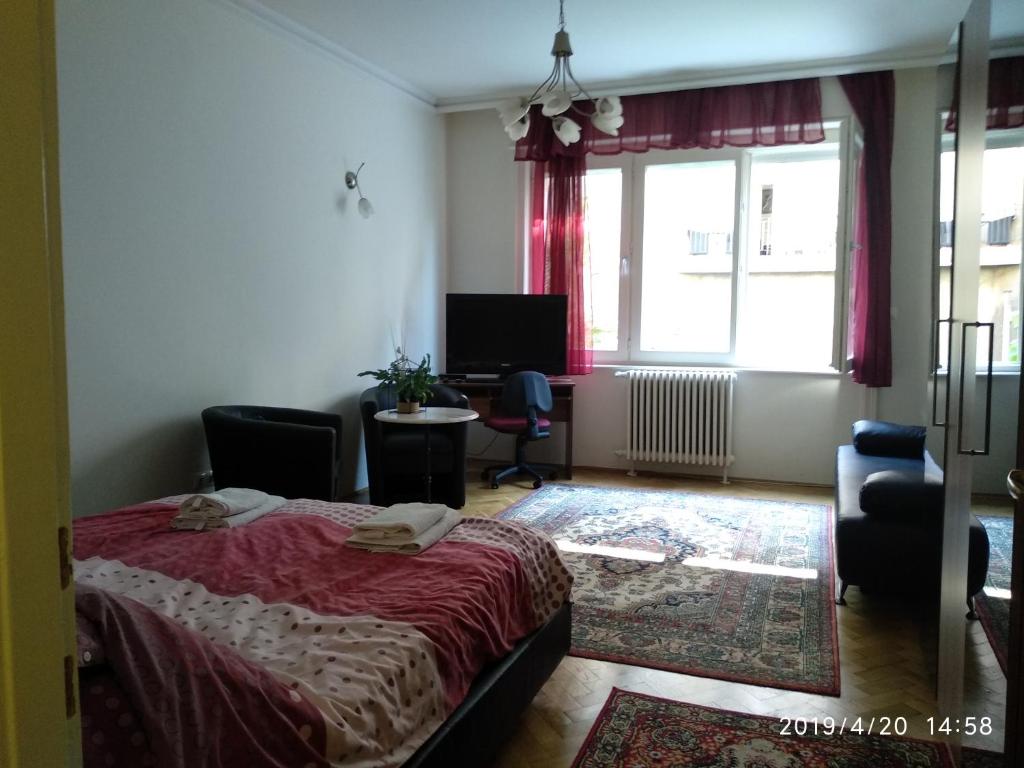 a bedroom with a bed and a desk and a window at Gyöngyi apartman in Budapest