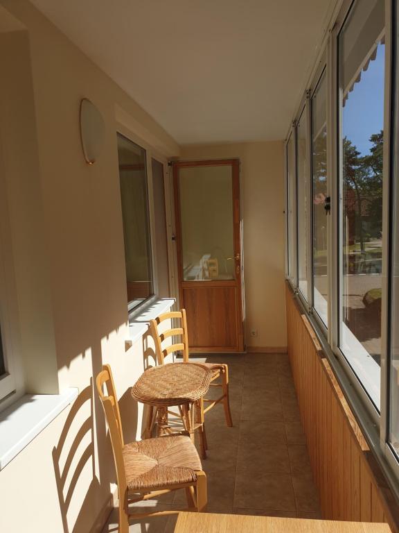 a porch with chairs and a table and windows at Apartamentai Taikos 10-36 Nida in Nida