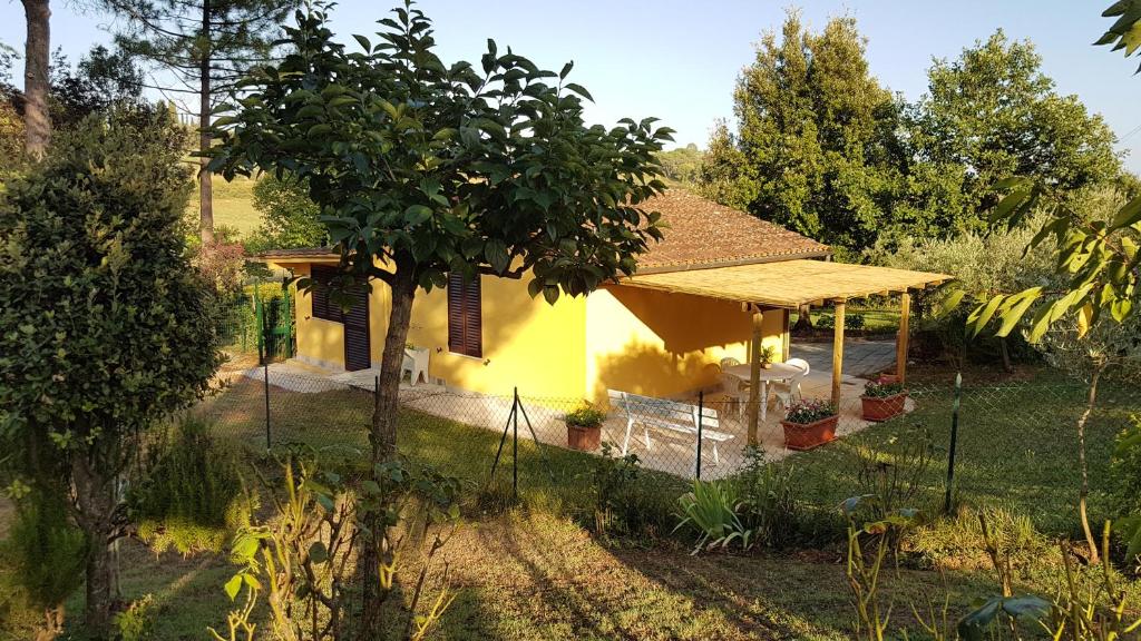 une petite maison jaune avec un arbre dans la cour dans l'établissement Casina Margherita, à Sienne