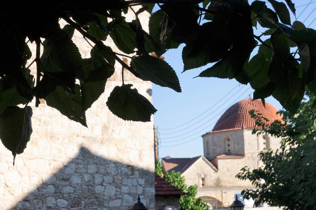 un edificio con una torre de reloj y un árbol en Salamiou Stone House, en Pafos