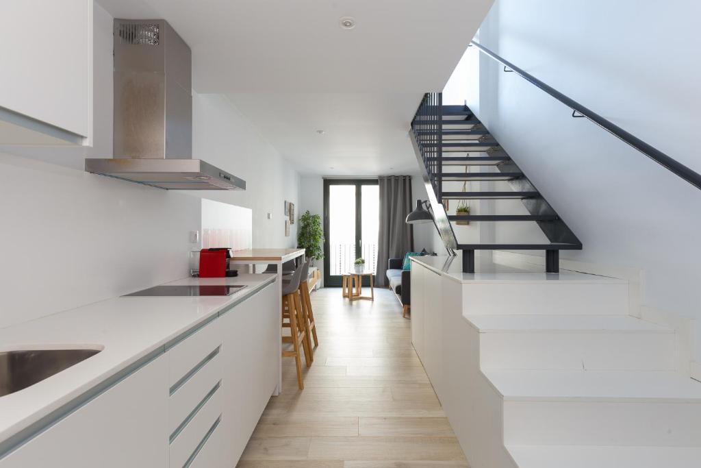 a kitchen with white countertops and a staircase at Urban Suites Sitges Apartments in Sitges