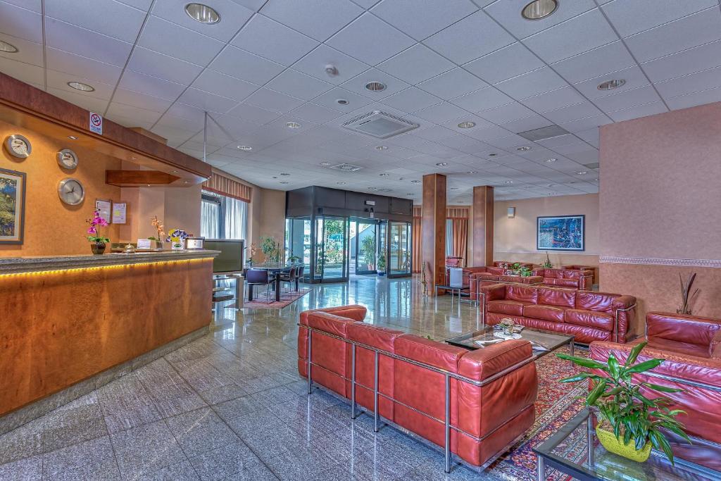 hol z meblami z czerwonej skóry i barem w obiekcie Gotha Hotel Turin Airport w mieście Ciriè