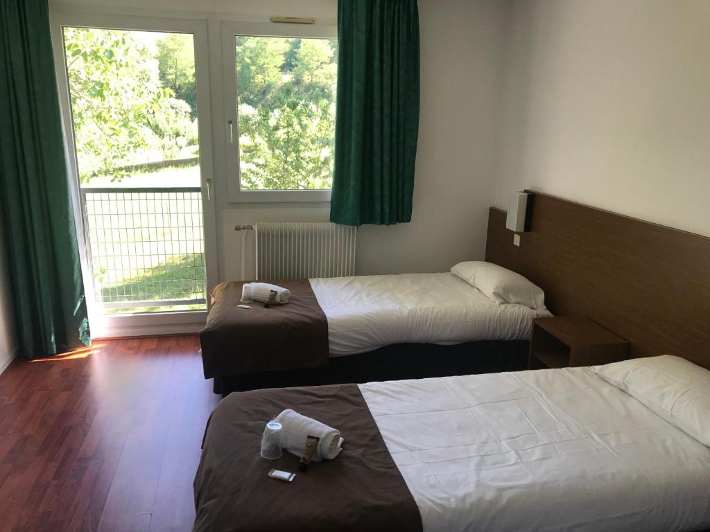 a hotel room with two beds and a window at Hôtel Restaurant L'Artière in Ceyrat
