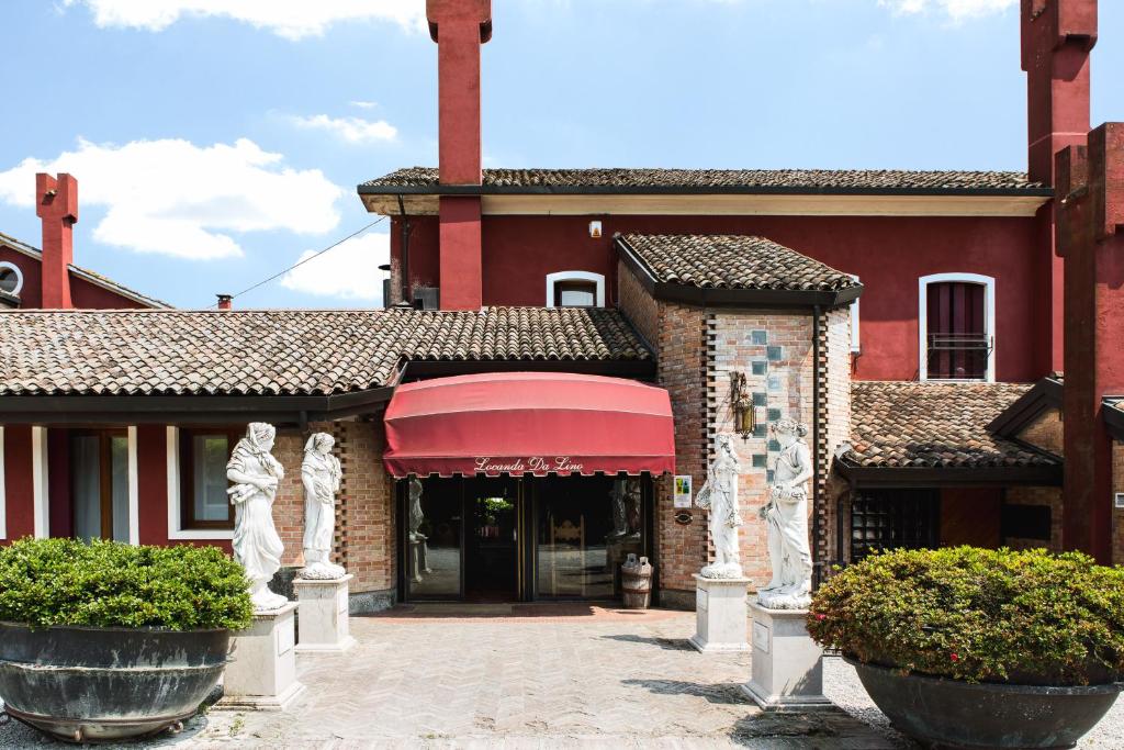 um edifício vermelho com duas estátuas em frente em Locanda Da Lino em Pieve di Soligo